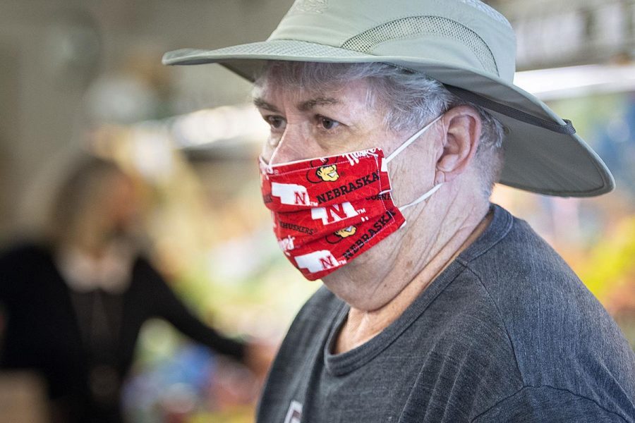 A man wears a Nebraska Huskers mask while in public. 