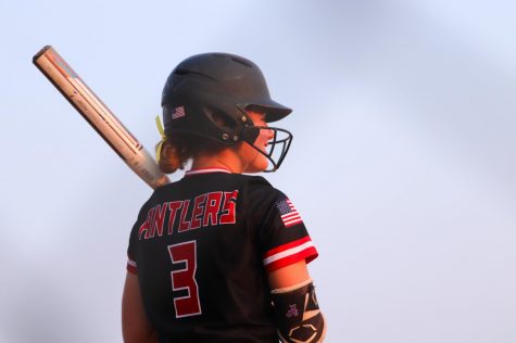 Senior Cam Cramer waits while Mya Larsen is up to bat. Cramer takes a break after practicing swings while Larsen plays. 