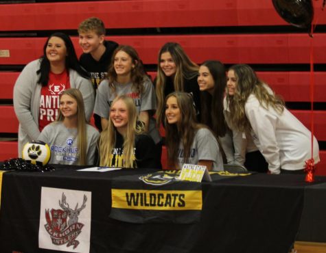Sydney Raszler, Taylor Bunjer and Hannah Fast celebrate signing day with their teammates and coach. All three seniors will play volleyball collegiately.