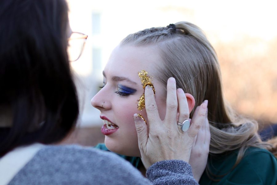 In preparation for their finals performance, members of Excel add glitter to the sides of their faces. The Excel glitter is a staple of the show choir that they have done for years. 