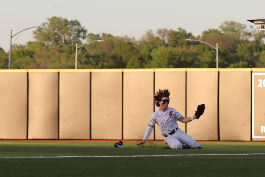 Cooper Fedde slides into the ground to catch a ball that Elkhorn North hit. Fedde caught the ball, resulting in an out for Elkhorn North. 