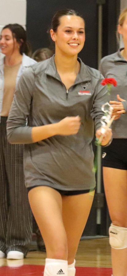Ella Schutte gives a flower to her parents during senior night. Schutte surpassed 1,000 career sets this season.