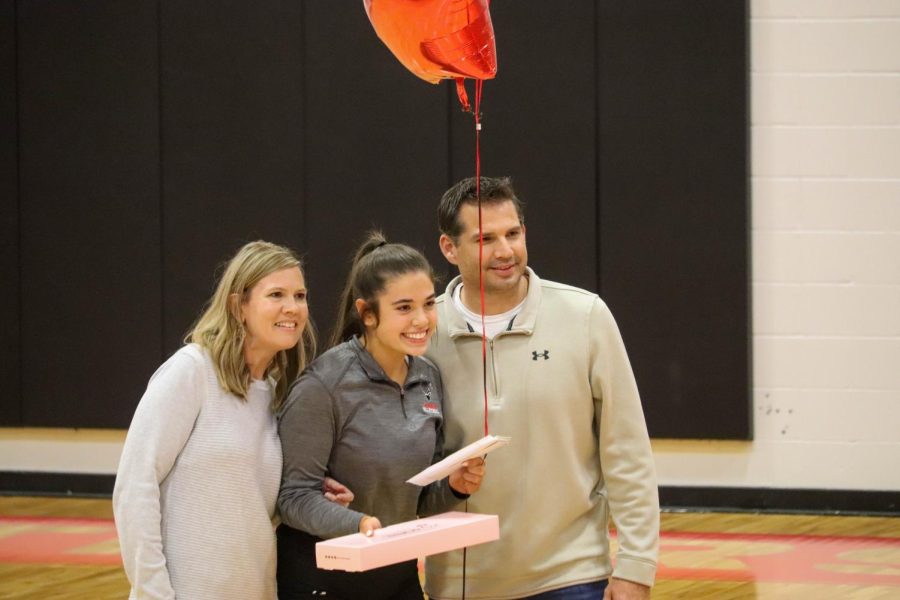 Avery Hoegh and her parents smile for a picture on senior night.
