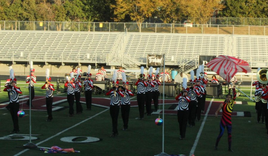 The Pride of the Antlers play their instruments while colorguard throws their flags in front of them. 