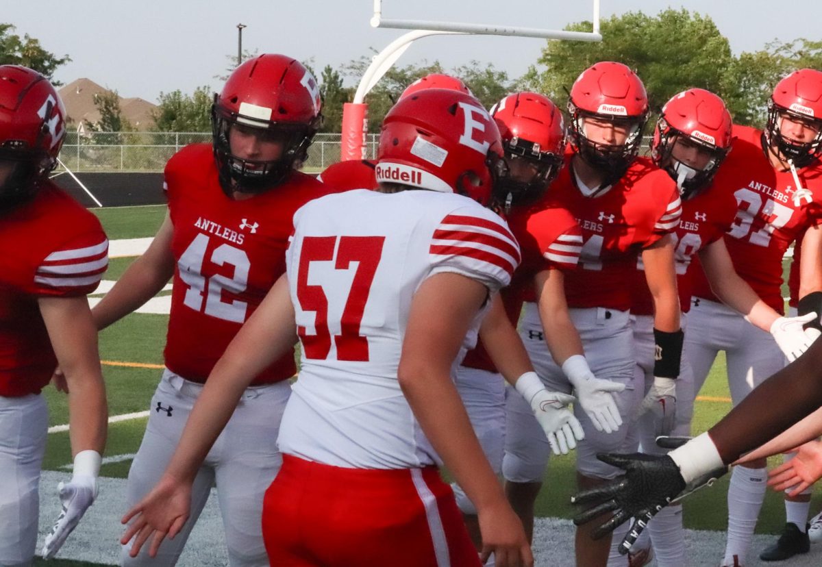 Sophomore Trevor Potter runs onto the field with his teammates hi-fiving him. Red beat White 62-7 on Friday, August 18th.