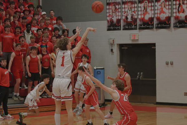 Senior Colin Comstock shoots a 3 pointer in the defenders face. Antler boys basketball team defeated Mt. Michael 67-56
