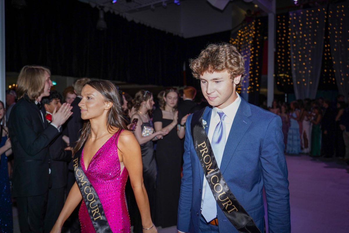 Seniors Gil Schroeder and Ella Prince walk through the crowd to get to coronation. 