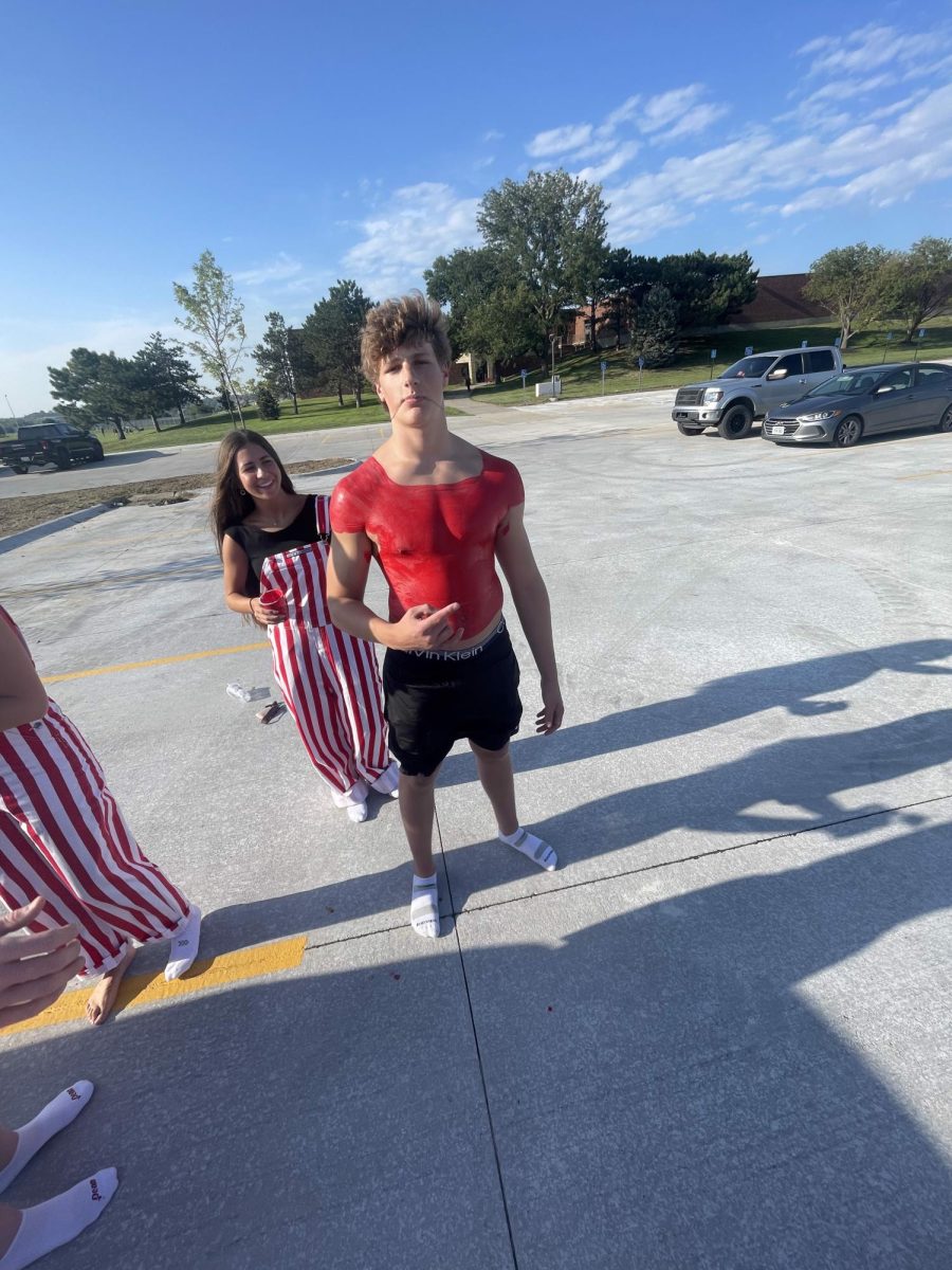 Senior Olivia Bailey is painting senior cade Dalton before Gatorade scrimmage. While waiting for paint to dry, Dalton poses for camera. 