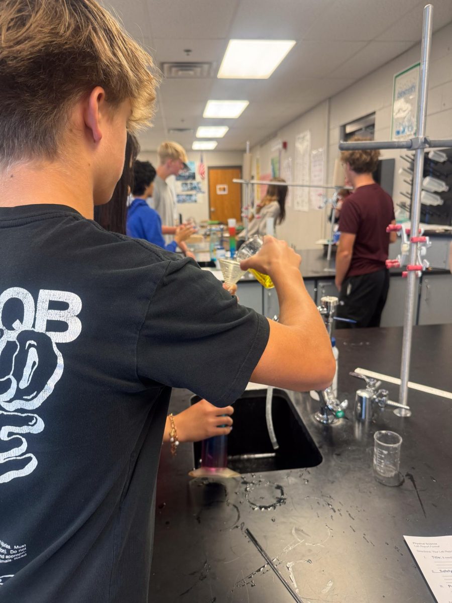 Mr. Stednitz freshmen class pour the different colored liquid through the funnel during their lab.