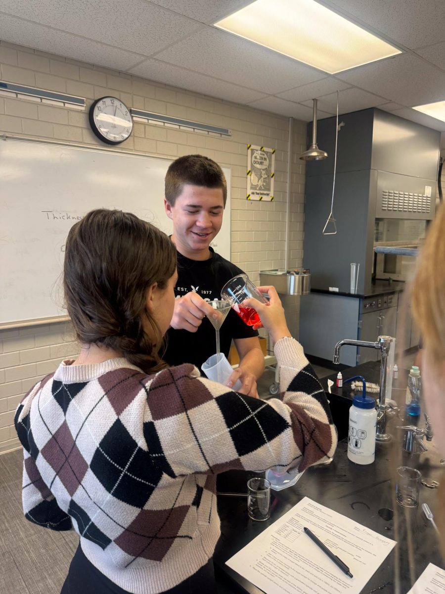 Freshman Everett Bailey and his partner pour their chemical mixture into their funnel during their lab.