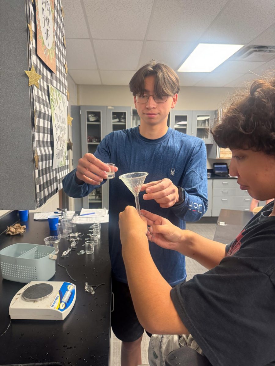 Juniors Ivan Ratnapradipa and Arshaan Adam pour sucrose into their dialysis bag during their AP Biology lab.