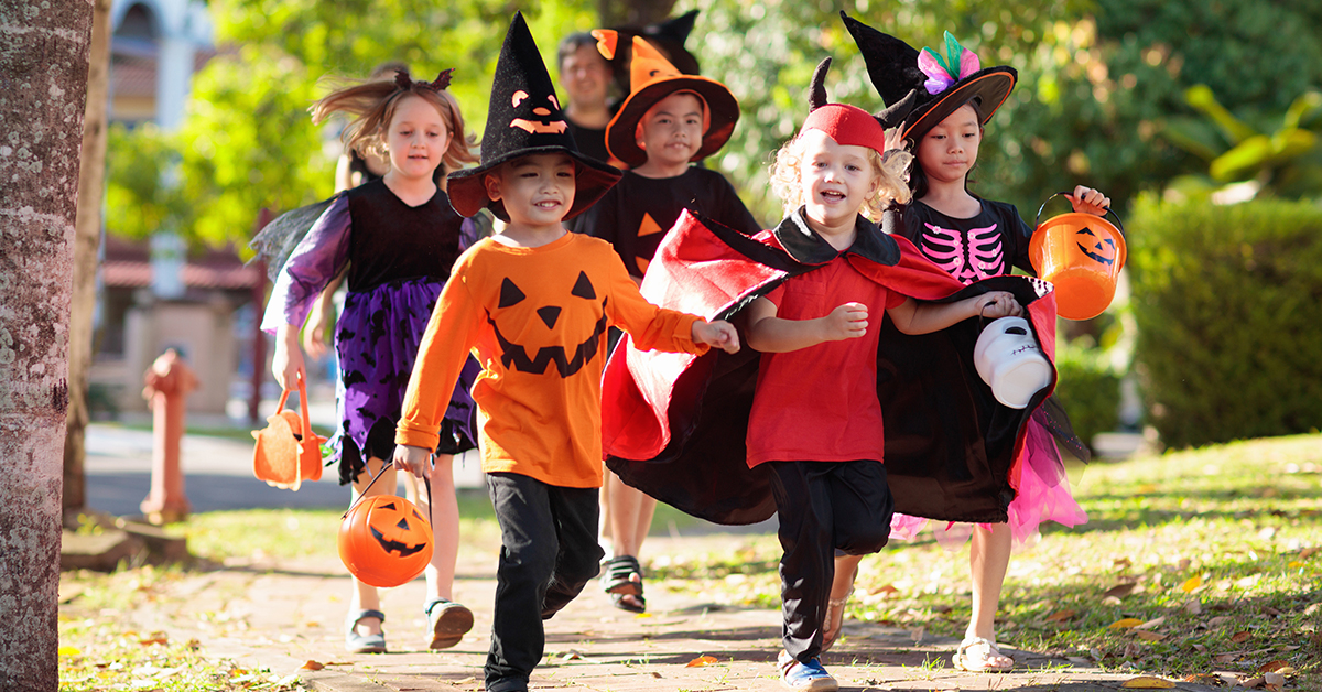 Various young children trick or treat on Halloween night.