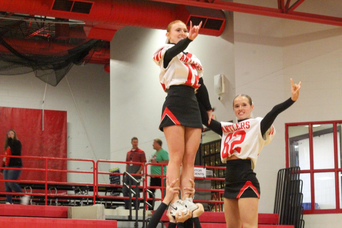 Senior Ayva Boekhout and sophomore Alyssa Wickett throw their antlers up as they stand in their pyramids. This took place during the Homecoming pep rally on Friday the 4th.