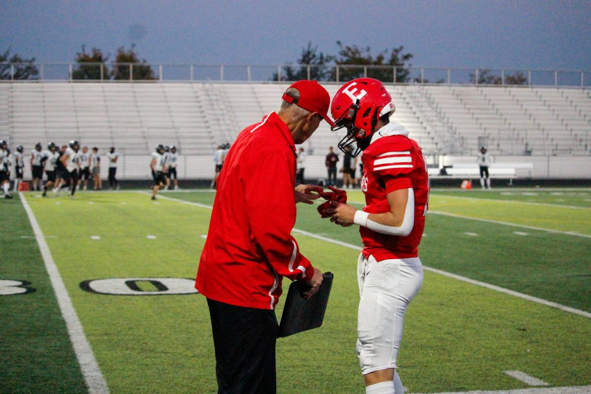 Coach Bacus hands sophomore Baron Clevenger his gloves. JV football plays North, final score ending 13-33.