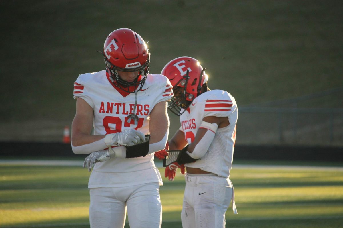 Senior Peyton Turman and senior Jayden Moody check their play cards from Coach Fieckert. 