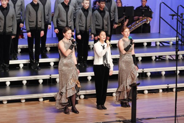 Junior Jamie Hemmingson, sophomore Kyla Burhan, and Elodie Bunting sing together at Red Carpet Classic.