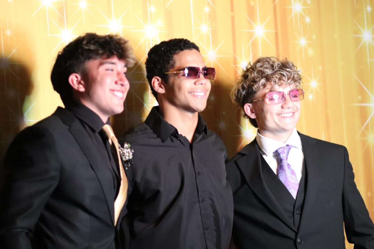 Senior boys smile for a picture while at prom.