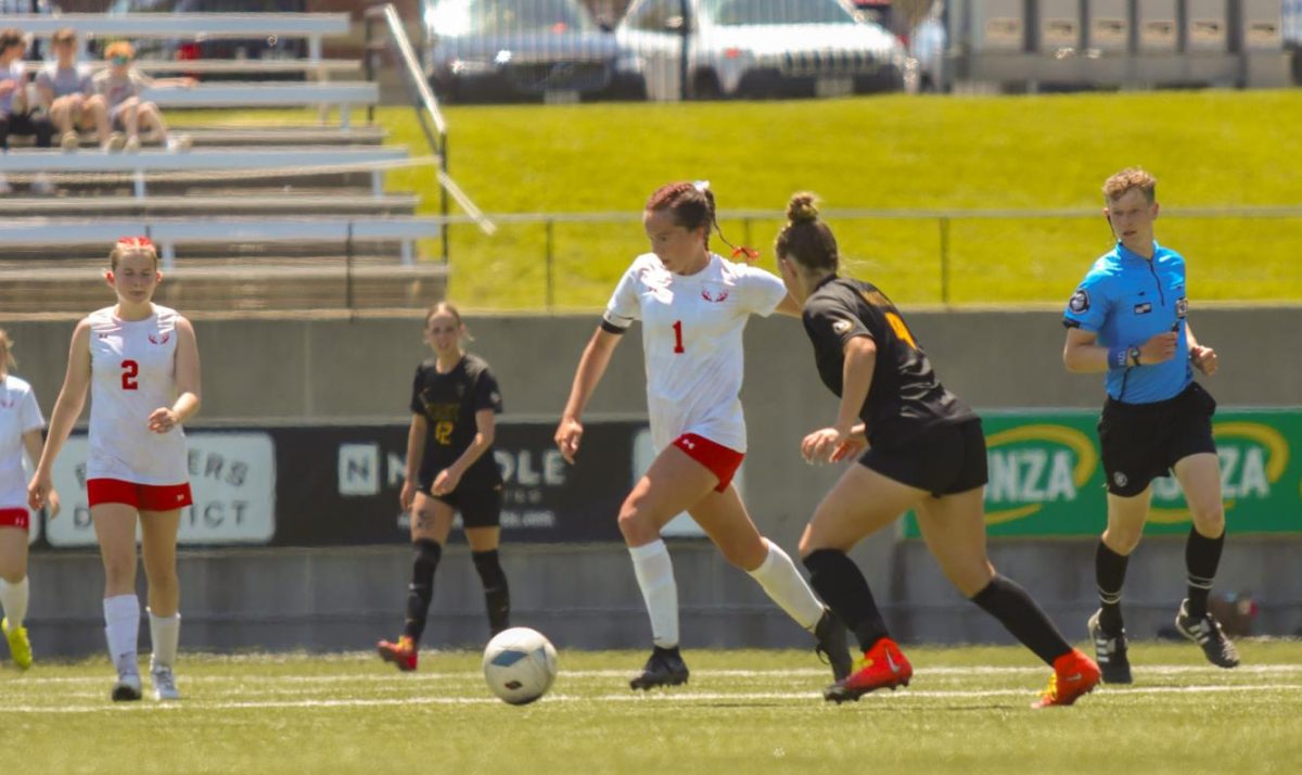 Junior Ella Rodgers dribbles past a Griffin defender during the state soccer game. The Antlers lost at state 6-2 to Gretna East.
