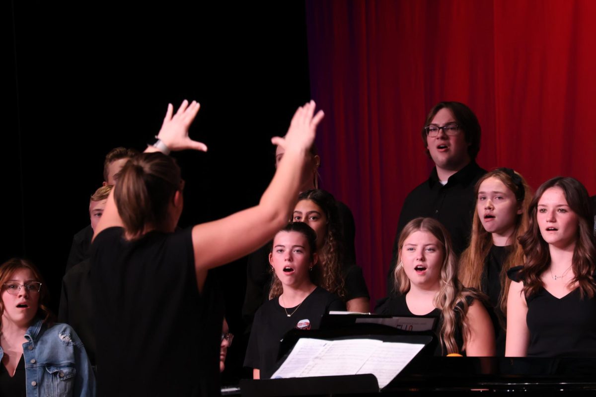 Teacher, Abby Thompson conducting the concert choir while they sing Zion's Wall.