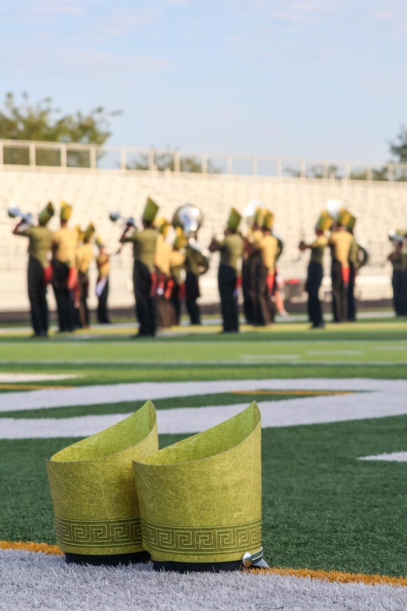 Two marching hats resting on the field as the band warms up before their performance. Elkhorn marching band performed on Oct. 11th, 2025.