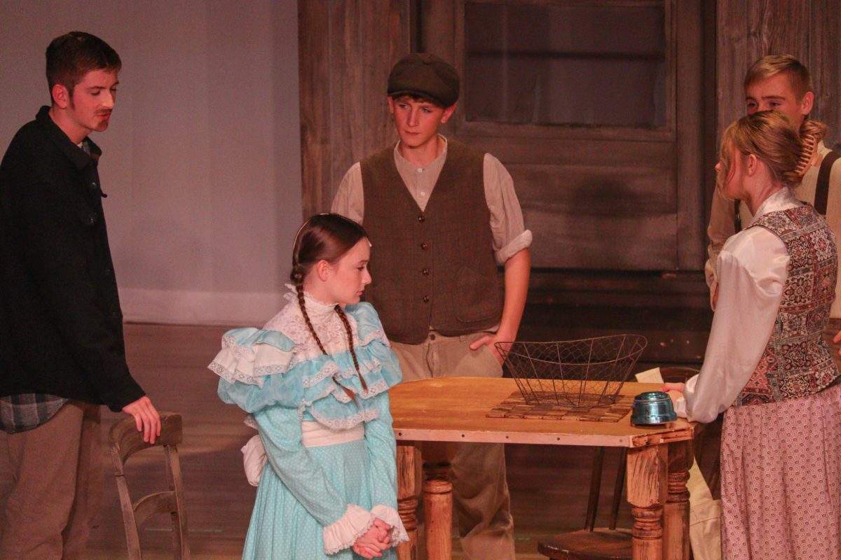 Seniors Christian Venditte, Nola Cowles, Gage Petrick, and sophomores Rylee Loonjer and junior Trevor Gross talk during the musical "Tuck Everlasting."