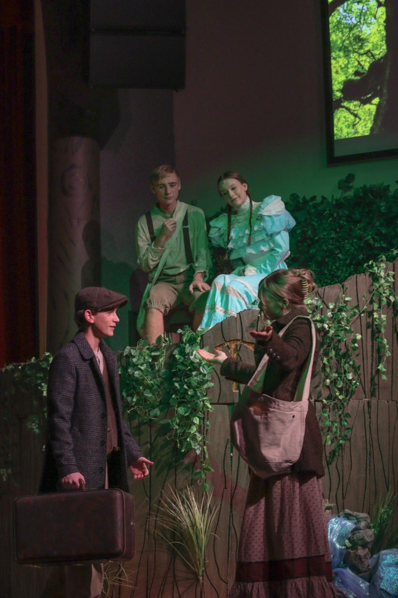 Seniors Gage Petrick and Nola Cowles spy on sophomores Rylee Loonjer and Trevor Gross from a tree in "Tuck Everlasting."