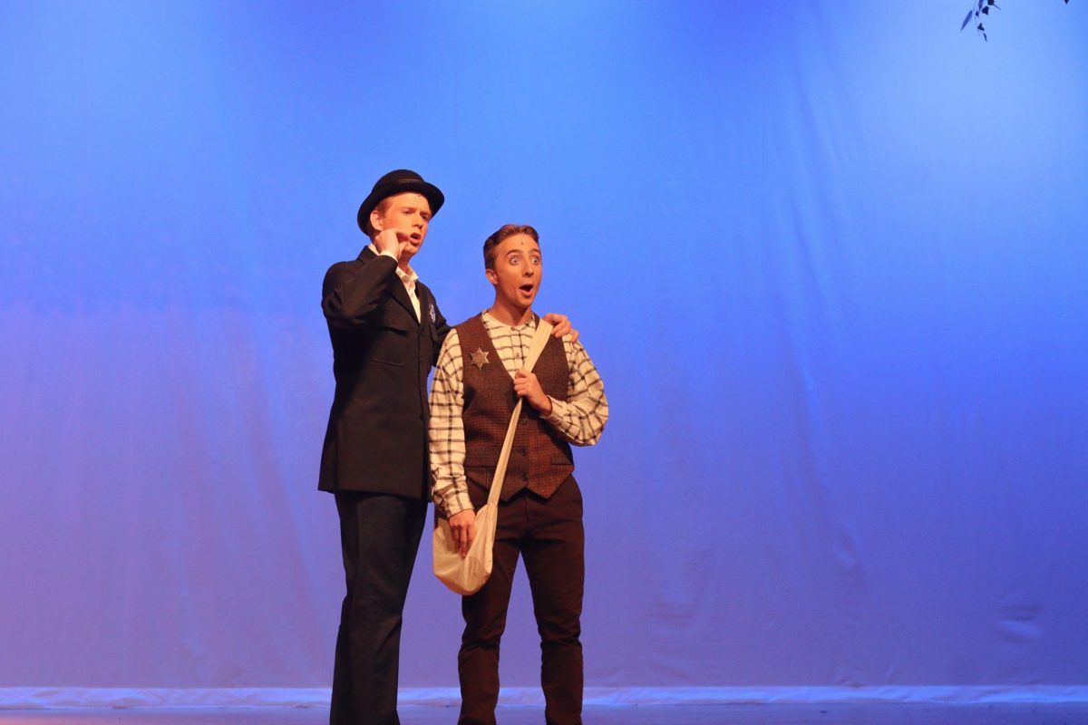 Junior Blake Warren explaining detective work to junior Kaleb Paulson in the musical "Tuck Everlasting."