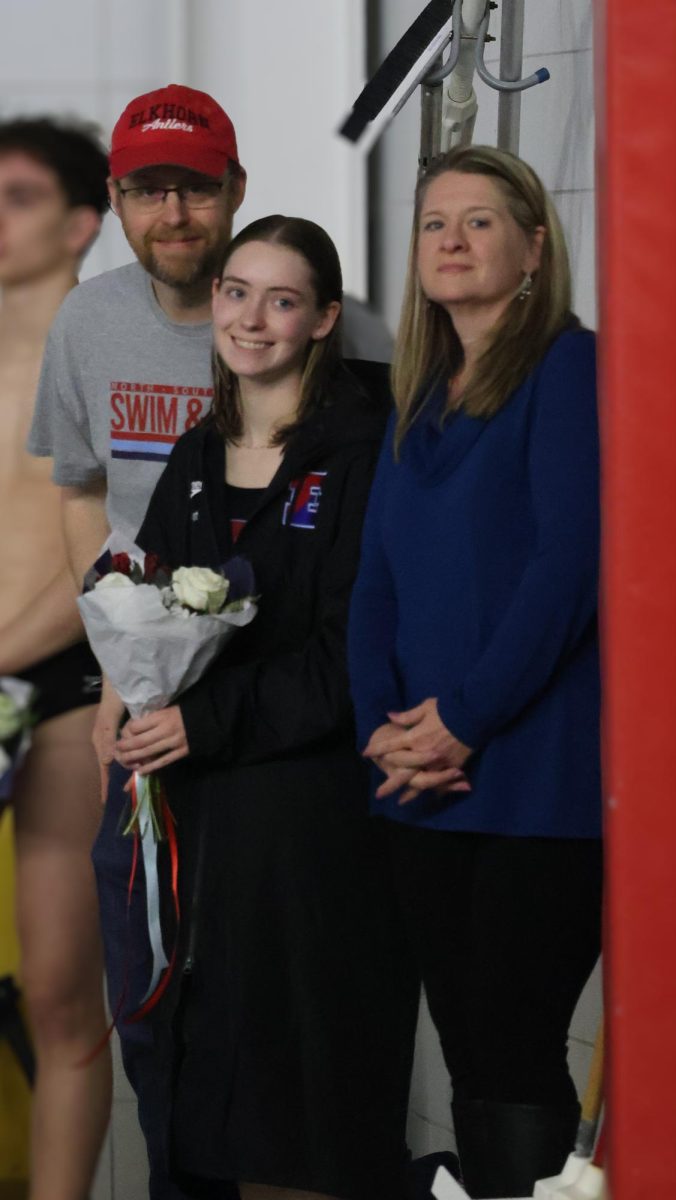 Senior Bridget Boster stands with her parents at senior night for swim and dive.