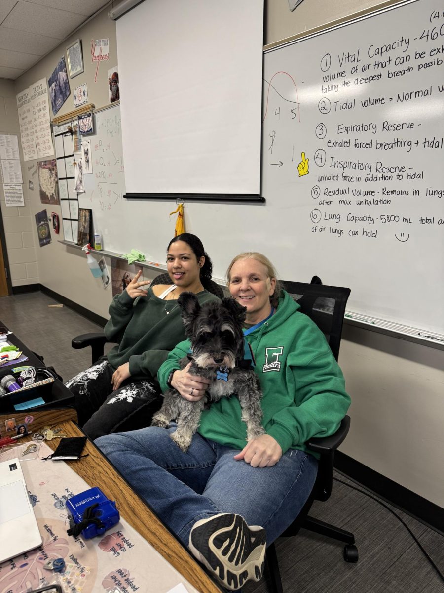 Junior Jasmine Burnett and science teacher Connie Bang share a relaxing moment Walter the therapy dog on Tree Day. 