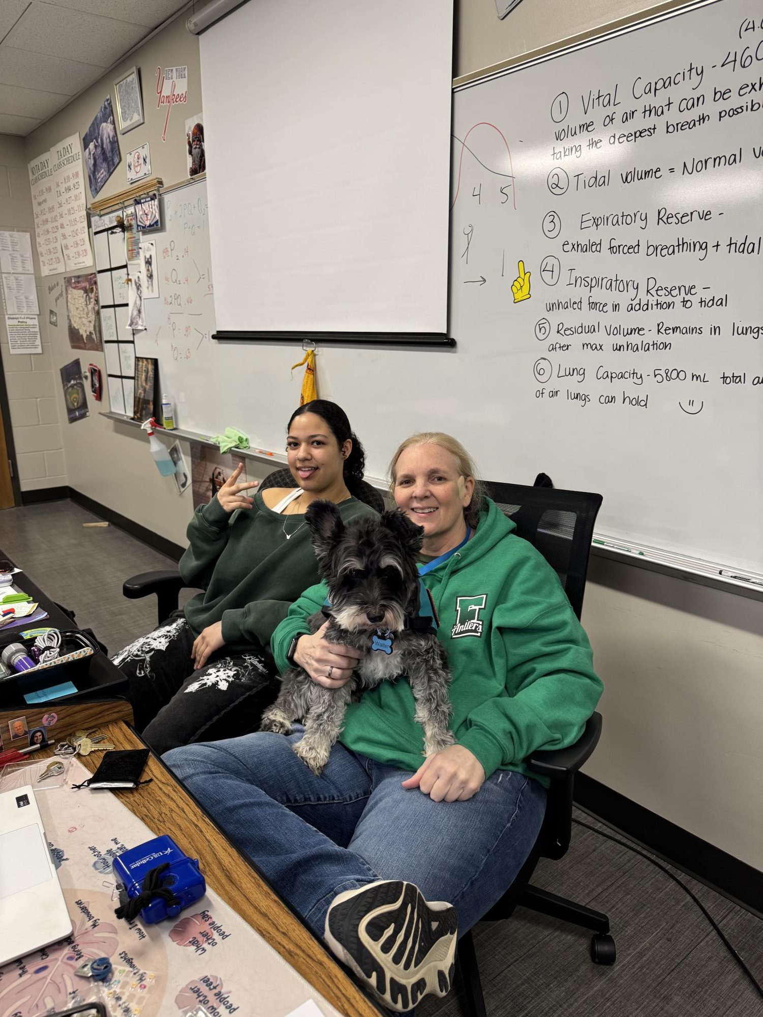 Junior Jasmine Burnett and science teacher Connie Bang share a relaxing moment Walter the therapy dog on Tree Day. 