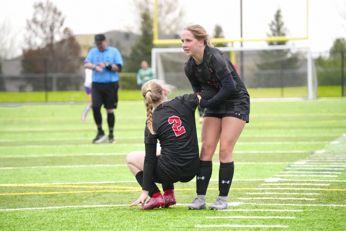 Freshman, Elly Thompson helping up her teammate after a goal was scored. 