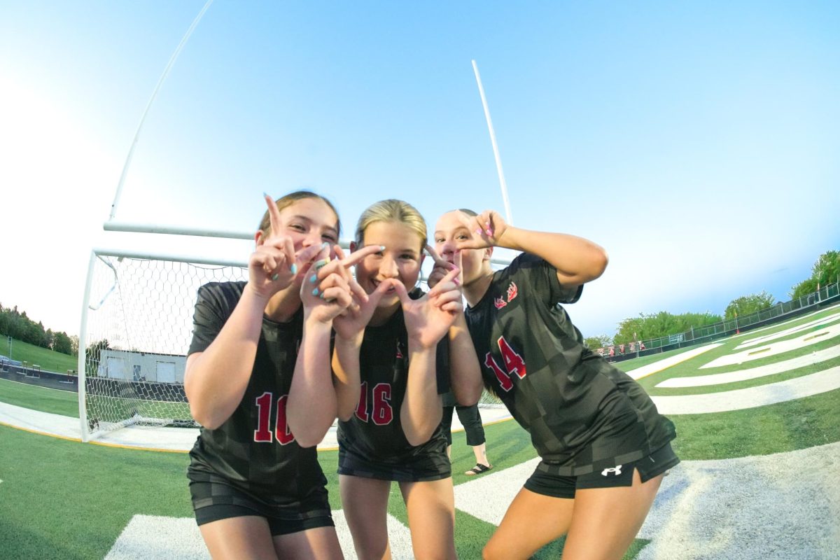 Freshman Olivia Pagan, Evie Rodgers, and Elly Thompson hold up a W after winning the district championship game. 